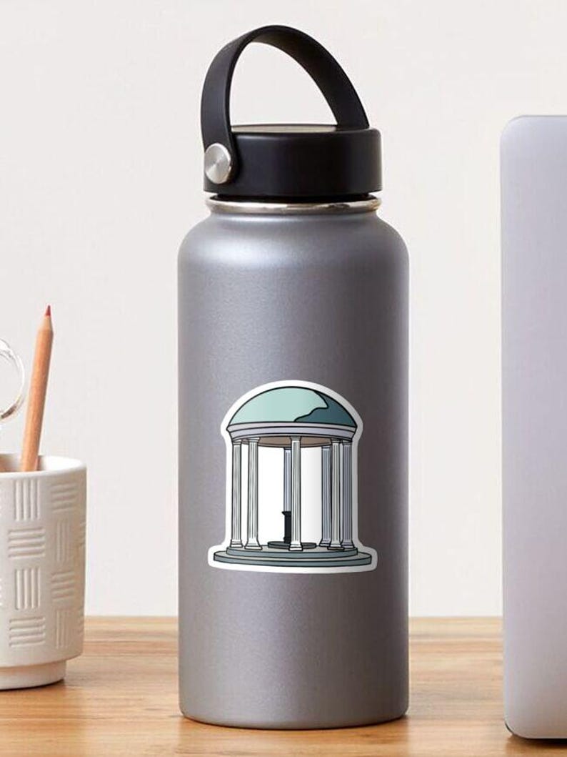 May include: A sticker featuring a teal and white illustration of a classical rotunda with columns and a domed roof. The sticker is applied to a gray water bottle with a black handle.