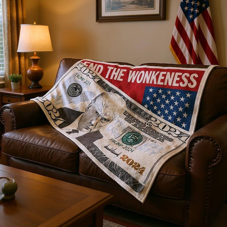 May include: A white and red blanket with a design resembling a $100 bill, featuring a portrait and the text "END THE WONKENESS" and "TRUMP 2024". The blanket is draped over a brown leather couch.