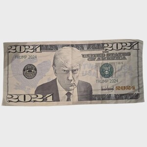 May include: A novelty item resembling a U.S. twenty-dollar bill, featuring a portrait of a man and the text "TRUMP 2024". The design includes the words "THE UNITED STATES OF AMERICA" and the year "2024" in multiple locations.