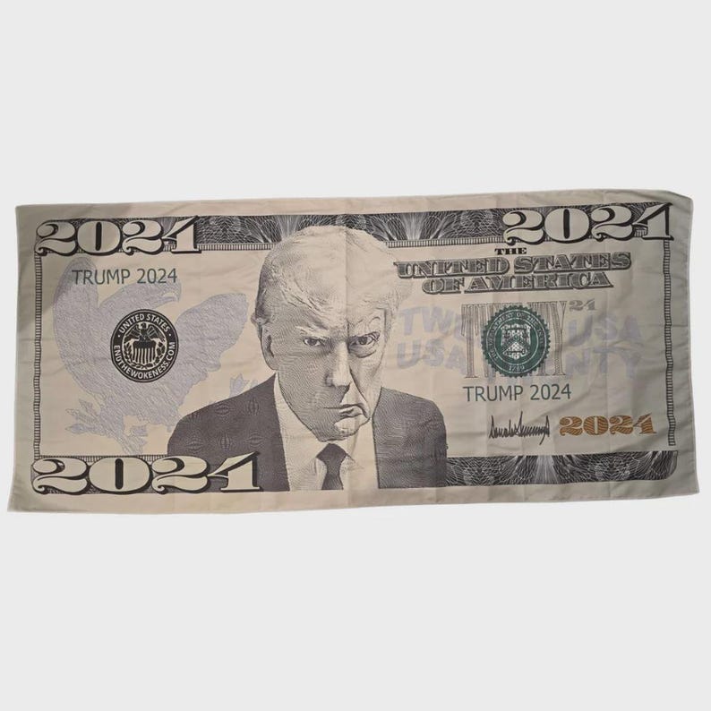 May include: A novelty item resembling a U.S. twenty-dollar bill, featuring a portrait of a man and the text "TRUMP 2024". The design includes the words "THE UNITED STATES OF AMERICA" and the year "2024" in multiple locations.