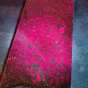 Peut inclure: Une œuvre d'art rectangulaire à la surface texturée. L'œuvre présente une palette de couleurs rose vif et brun foncé, avec des éclaboussures et des taches roses sur toute la surface. Les bords sont irréguliers, ce qui lui donne un aspect brut et fait à la main.