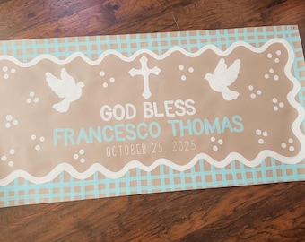 May include: A banner with a light brown center, a white wavy border, and a light blue checkered pattern. The banner has the words "GOD BLESS FRANCESCO THOMAS OCTOBER 25 2025" and features a cross and two doves.