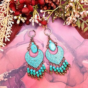 Puede incluir: Un par de pendientes colgantes de color turquesa y cobre con un diseño de media luna y cuentas turquesas.