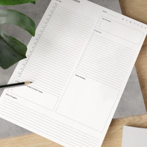 May include: A white daily planner with a black header that says "Daily Planner". The planner has sections for "Your Day", "Top Priorities", "To-Do List", "Notes & Ideas", and "Extra Thoughts".
