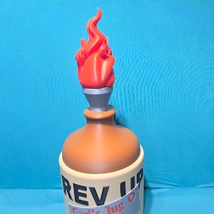 May include: A beige jug with a brown neck and a red flame-shaped topper. The jug features black text reading REV UP and a label with the text Carl's Jug O' BOOM in red and blue, with black zigzag graphics at the bottom of the cylindrical container.