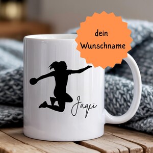 Könnte beinhalten: Weiße Keramiktasse mit einer schwarzen Silhouette einer Person, die Sport treibt, und dem Namen "Jagci" in Schreibschrift. Eine orangefarbene Sternform mit dem Text "dein Wunschname" ist ebenfalls sichtbar. Die Tasse steht auf einer Holzoberfläche.
