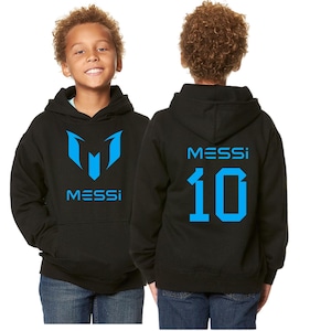 May include: Black hoodie with a blue logo and the name "MESSI" printed on the front. The back of the hoodie features the name "MESSI" and the number "10" in blue. The hoodie is worn by a child.
