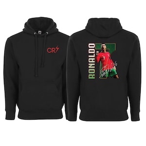 May include: Black hoodie featuring a red "CR7" logo on the front. The back displays a graphic of a soccer player in a red jersey with the name "RONALDO" vertically and his signature.