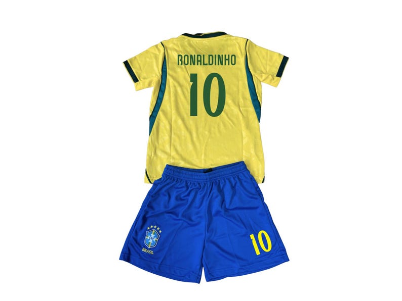 May include: A yellow and blue soccer uniform set. The jersey has the name "RONALDINHO" and the number "10" on the back. The shorts are blue with the number "10" and a team emblem. The uniform is likely for a youth.
