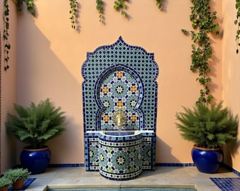 May include: A decorative outdoor fountain with a mosaic tile design in shades of blue, green, and gold. The fountain has a curved arch shape and a small basin. Two large blue ceramic pots with green plants flank the fountain.