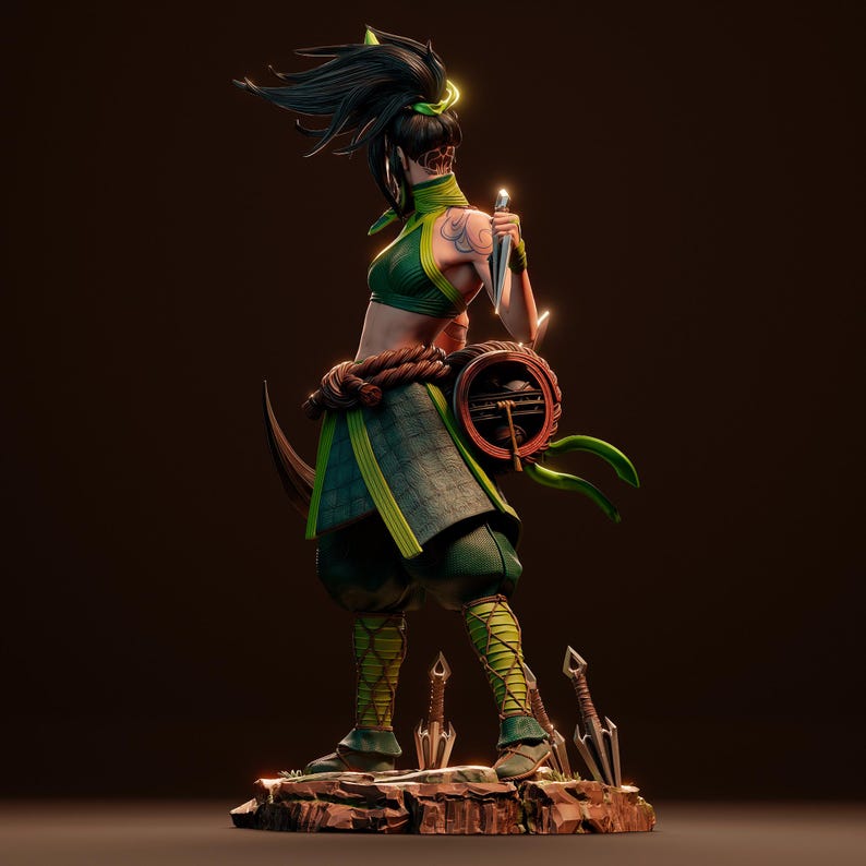 May include: A green and black action figure of a female character with long black hair, a green and black outfit, and a weapon. The figure is posed in a fighting stance with a weapon in her hand. The figure is standing on a rocky base with several smaller weapons scattered around it.