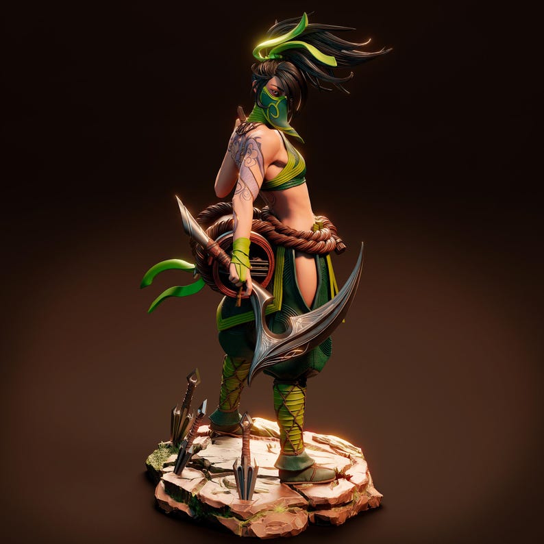May include: A green and black figurine of a female warrior with a green mask, holding a curved blade and a green and brown shield. The figurine is standing on a rocky base with several small blades scattered around it.