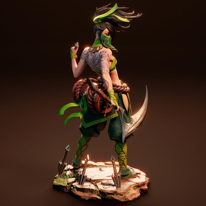 May include: A green and black action figure of a female character with long black hair, a green mask, and a green and black outfit. The figure is holding a curved blade and is standing on a rocky base.