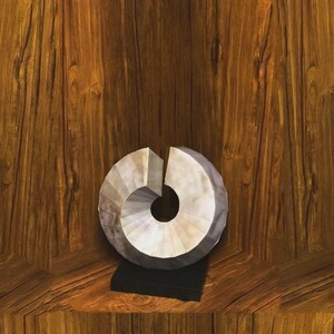 May include: A decorative, abstract sculpture with a spiral design. The sculpture is primarily white and gray, with a dark gray base. It sits on a wooden surface with a rich, brown grain.