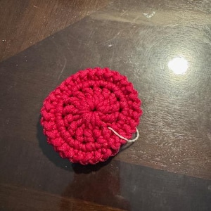 May include: A bright pink crocheted flower with a white thread attached to the center.