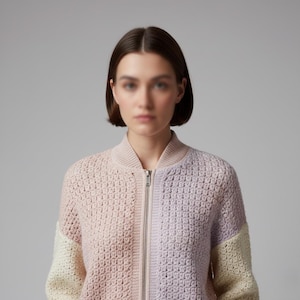 May include: A color-blocked, zip-up bomber jacket in a crochet knit. The jacket features a split design with sections of pale pink, lavender, and cream. The collar and cuffs are a solid pale pink. The zipper is silver.