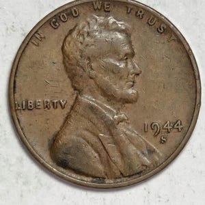 May include: A copper-colored 1944 Lincoln penny. The obverse features a profile of Abraham Lincoln, the word "LIBERTY", and the inscription "IN GOD WE TRUST". The year "1944" and the mint mark "S" are also visible.