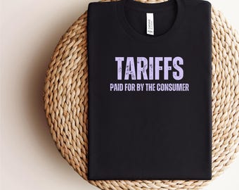 May include: Black t-shirt with the text "TARIFFS PAID FOR BY THE CONSUMER" in purple.