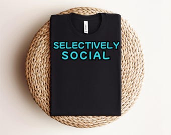 May include: Black t-shirt with the text "SELECTIVELY SOCIAL" in turquoise blue.
