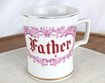 Peut inclure: Tasse en céramique blanche avec le mot "Father" en script rouge, encadré de motifs floraux et de volutes roses. La tasse a un bord et une anse dorés, et est probablement vintage. Hauteur d'environ 10 cm.