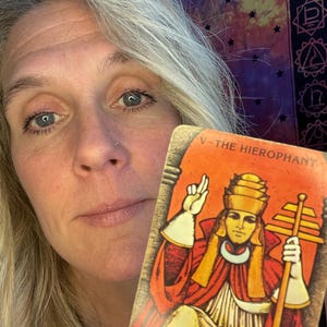 Może przedstawiać: Karta tarota z obrazem mężczyzny w koronie i czerwonej szacie. Karta jest oznaczona jako "V - Hierofanta".