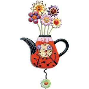 May include: A red teapot with a black handle and spout, decorated with black vines and red dots. The teapot has a clock face with black and white hands and a pendulum. The teapot is filled with colourful flowers, including purple, pink, yellow, and red.