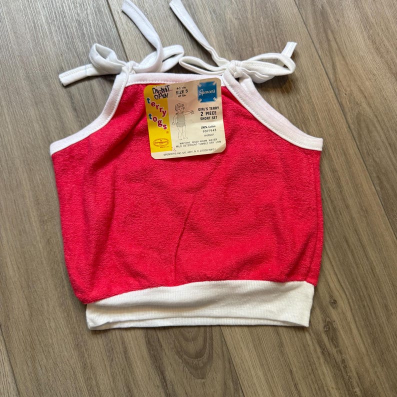 Może przedstawiać: Vintage r&oacute;żowy top z frotte z białym wykończeniem i ramiączkami. Top ma metkę z napisem "Girl's Terry 2 Piece Short Set". Top jest w rozmiarze S.