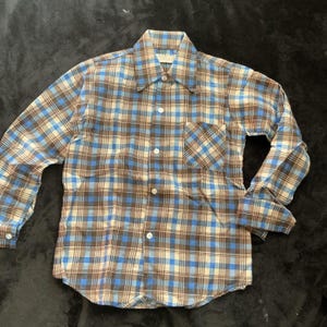 Op de afbeelding: Een geruit shirt met lange mouwen in blauwe, bruine en crèmetinten. Het shirt heeft een knoopsluiting, een borstzak en manchetten met knopen. Het klassieke patroon is over het hele shirt zichtbaar.