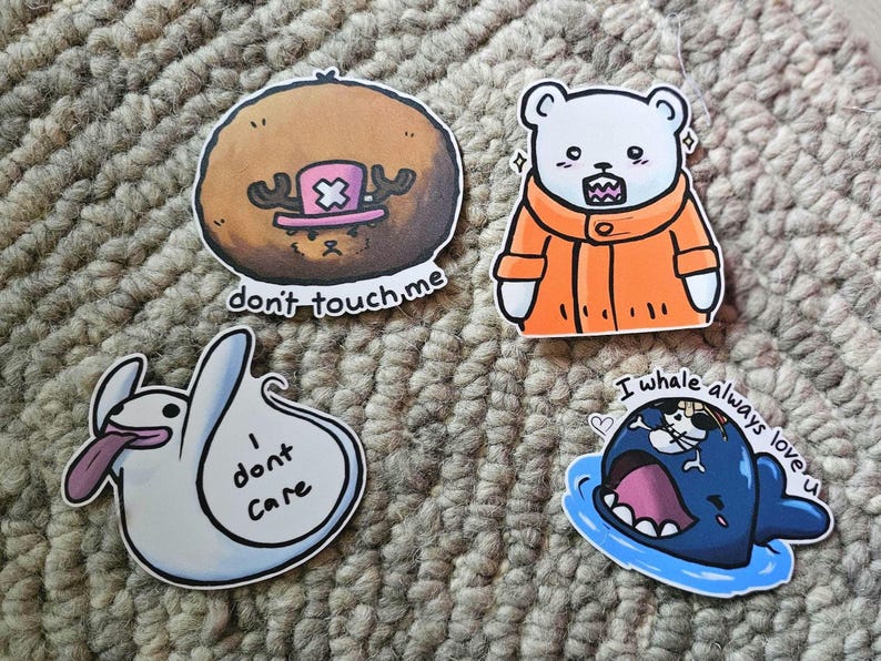 May include: Four colourful stickers with cartoon characters and text. The first sticker is brown with a pink and white hat and the text "don't touch me". The second sticker is white with an orange jacket and the text "I whale always love u". The third sticker is white with a ghost and the text "I don't care". The fourth sticker is blue with a whale and a small white character inside the whale's mouth.