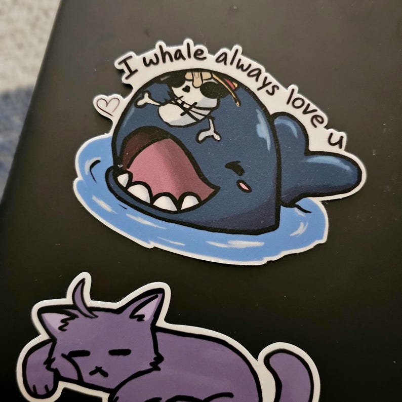 May include: A blue whale with a skull and crossbones on its head, with the text "I whale always love u" in a white circle around it. The whale is in the water and has a pink mouth open.