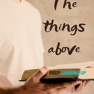 May include: An open book held by a person, featuring the title "The things above" in a handwritten style. The text "KEEP LOOKING UP" is visible, along with the author's name, "EDUARDO CALSAVARA". The book has a tan cover and black binding.