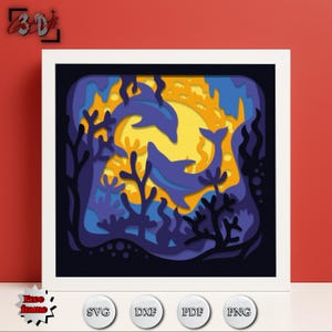 May include: A framed, layered paper art piece featuring two leaping dolphins in a vibrant underwater scene. The artwork uses shades of blue, yellow, and orange to depict the ocean, sun, and coral. The frame is white, and the image includes the text "Free frame", and SVG, DXF, PDF, and PNG icons.