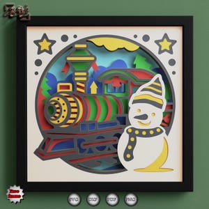 May include: A layered paper art piece featuring a colorful train and a snowman inside a circular frame. The train is red, green, and yellow, and the snowman wears a hat and scarf. The artwork is set in a black frame.