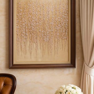 Puede incluir: Una obra de arte enmarcada con un fondo beige texturizado y elementos florales claros en cascada. La obra de arte est&aacute; encerrada en un marco de madera marr&oacute;n oscuro. Un ramo de rosas blancas se encuentra en un jarr&oacute;n blanco sobre una mesa.