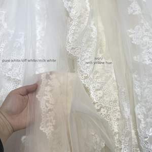 May include: A display of bridal fabrics in various shades of white and cream. The image shows samples labeled "pure white/off white/milk white", "ivory with yellow hue", and "champagne - red hue". The fabrics include delicate lace and tulle.