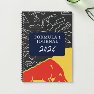 May include: Spiral-bound Formula 1 Journal for 2026. The cover features a black background with white track outlines, a navy blue rectangle with the text "FORMULA 1 JOURNAL 2026", and a red bull graphic over a yellow background.
