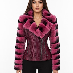 Könnte beinhalten: Eine magenta-schwarze Pelzjacke mit Schlangenleder-Struktur auf der Vorderseite. Die Jacke hat einen Reißverschluss, einen Pelzkragen und Pelzbündchen. Die Ärmel sind eine Kombination aus magenta- und schwarzem Pelz. Ein stilvolles Oberbekleidungsstück.