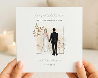 May include: A square white wedding greeting card featuring the text Congratulations ON YOUR WEDDING DAY, Mr & Mrs Wannen, and 18.05.2025. The illustration shows a couple from behind, a person in a white gown and a person in a black suit, inside a gold frame.