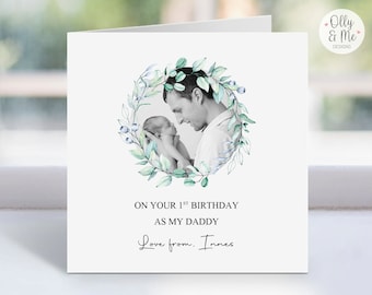 May include: A black and white photo of a father holding a baby in a leafy green wreath. The text reads "On your 1st birthday as my daddy. Love from. Innes."
