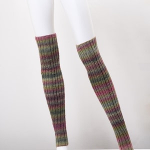 May include: A pair of knitted leg warmers in a ribbed pattern. The leg warmers feature a blend of colors, including green, purple, and brown. The leg warmers are displayed on a white mannequin.