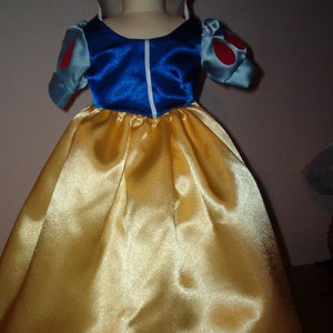 K&ouml;nnte beinhalten: Ein gelbes Satinkleid mit einem blauen Satin-Mieder und wei&szlig;en Besatz. Das Kleid hat Puff&auml;rmel mit roten Akzenten.
