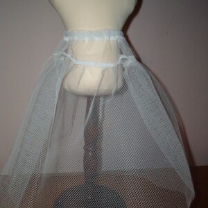 K&ouml;nnte beinhalten: Wei&szlig;er T&uuml;ll-Petticoat mit gerafftem Bund. Der Petticoat wird auf einer Schaufensterpuppe pr&auml;sentiert.