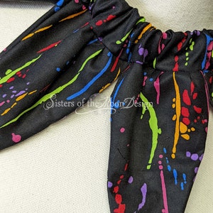 May include: Black fabric with a colorful paint splatter design. The fabric has a gathered elastic band at the top.