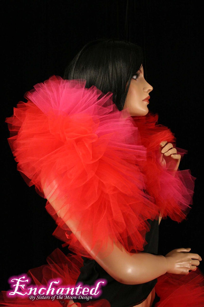 May include: A red and pink tulle boa with a ruffled texture. The boa is worn around the neck of a mannequin.