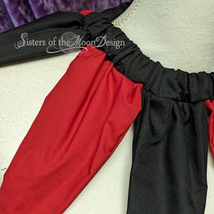 K&ouml;nnte beinhalten: Nahaufnahme einer roten und schwarzen Stoffkappe mit gerafftem Ausschnitt. Der Stoff ist weich und flie&szlig;end. Der Text "Sisters of the Moon Design" ist auf der Kappe sichtbar.