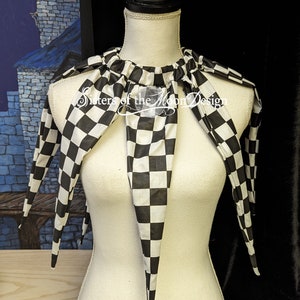 May include: A black and white checkered fabric collar with long, pointed ends. The collar is on a white dress form. The text "Sisters of the Moon Design" is visible on the collar.