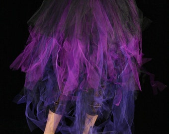 May include: A black and purple tulle skirt with a gradient effect. The skirt is layered and has a ruffled hem. It is being worn by a mannequin.