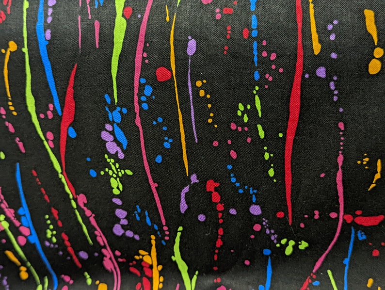 May include: Black fabric with a colorful abstract pattern of splattered paint and streaks. The colors include red, orange, yellow, green, blue, and purple.