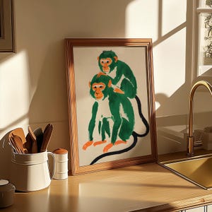 May include: A framed illustration of two green monkeys sitting on a white background. The monkey on top is looking to the right, while the monkey on the bottom is looking to the left. The monkeys are painted in a stylized, almost cartoonish style.