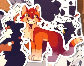 May include: A selection of cat-themed stickers in various colours. The stickers depict cartoon cats in shades of orange, red, black, and white. The cats are shown in different poses and expressions, some smiling. The stickers are die-cut with a white border.